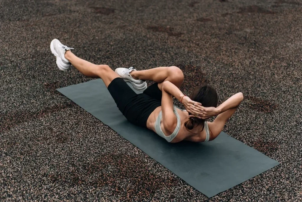 Fit woman doing a bicycle crunch on a mat outdoors, emphasizing core strength and fitness.