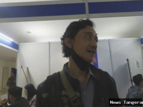 Pria paruh baya di bursa kerja, memakai masker di dagu, mencari pekerjaan.