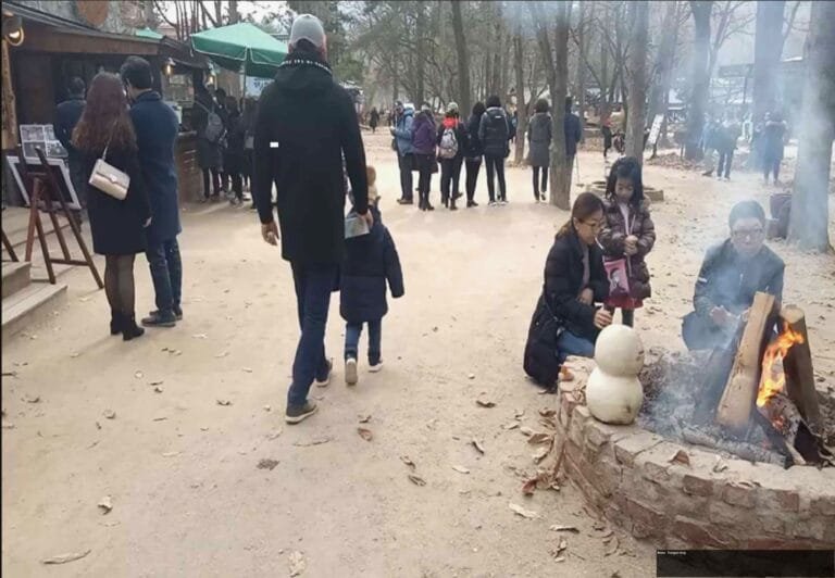 Pengunjung Pulau Nami menghangatkan diri di dekat perapian saat musim dingin.