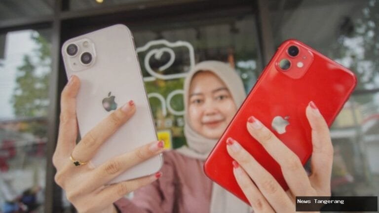 Seorang wanita memegang dua iPhone berwarna putih dan merah.