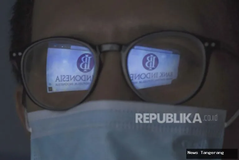 Refleksi logo Bank Indonesia pada kacamata, fokus pada kebijakan moneter dan ekonomi.
