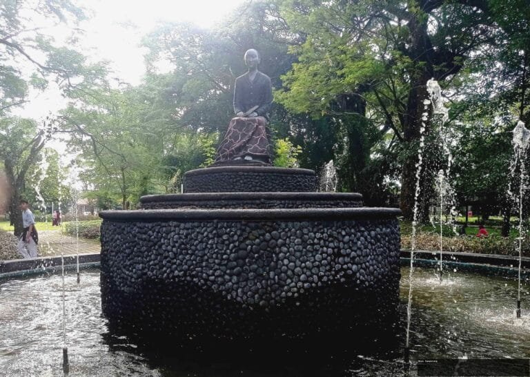 Air mancur bertingkat dengan patung wanita di taman Solo, suasana tenang.