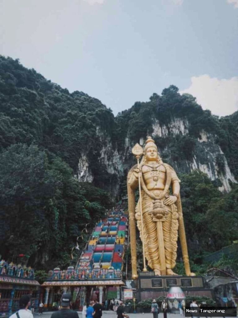 Patung Dewa Murugan emas raksasa di depan tangga warna-warni Batu Caves.