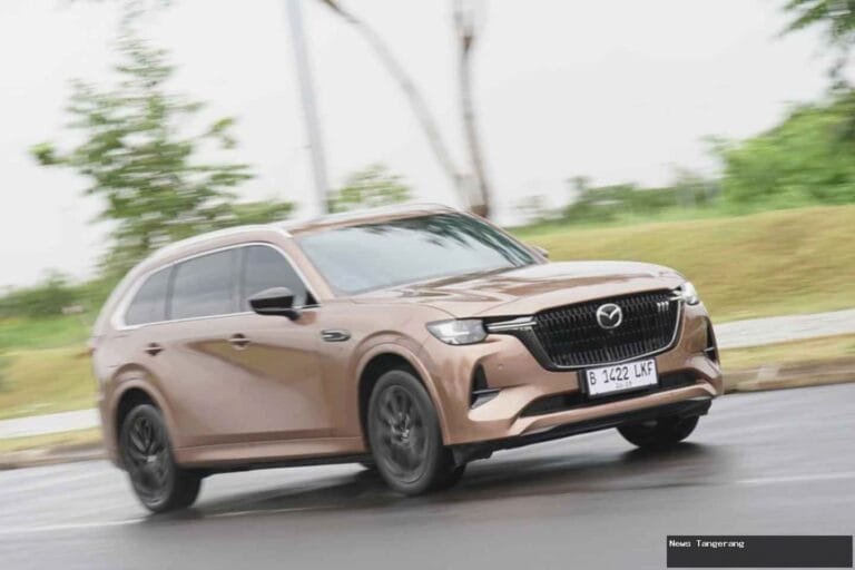 Mazda CX-80 PHEV warna cokelat melaju di jalan beraspal, tampak depan.