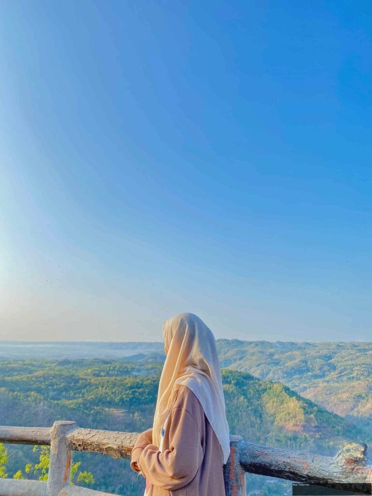 Wisatawan berhijab menikmati pemandangan perbukitan Mangunan saat cuaca cerah.