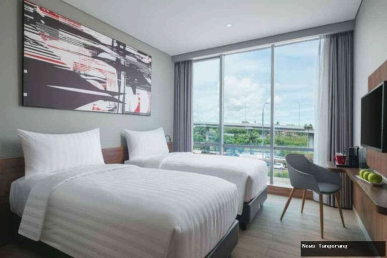 Kamar hotel Neo dengan dua tempat tidur, jendela besar, dan pemandangan kota.