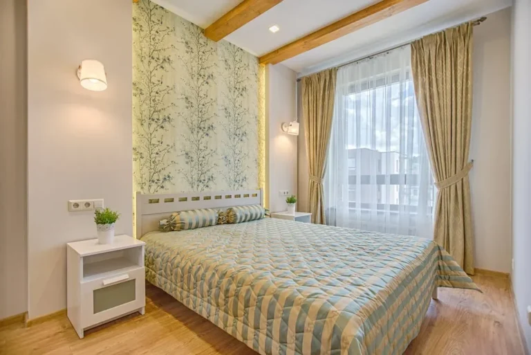 A luxurious and contemporary bedroom design with patterned wallpaper and natural lighting, located in Vilnius, Lithuania.