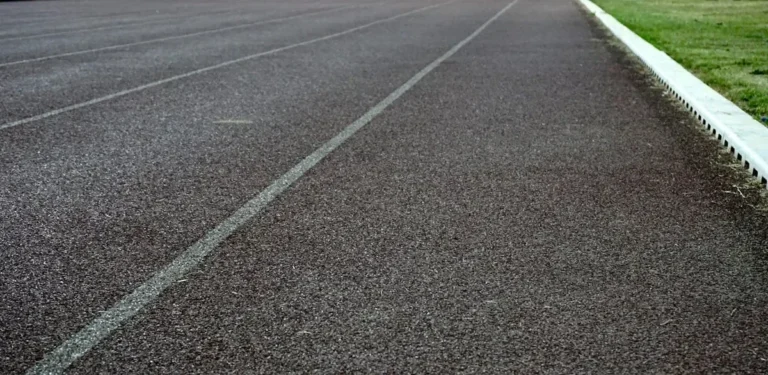 Detailed view of an empty athletic running track lane with visible surface texture and grass edge.
