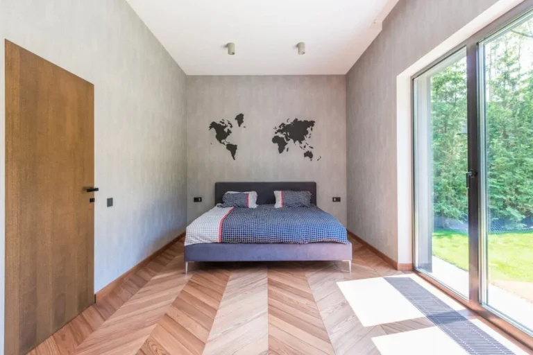 Spacious and minimalist bedroom with a world map wall decor, featuring natural light and modern design elements.