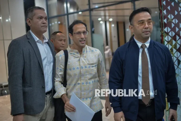 Nadiem Makarim bersama dua orang pria berjalan di dalam gedung, terlihat santai.