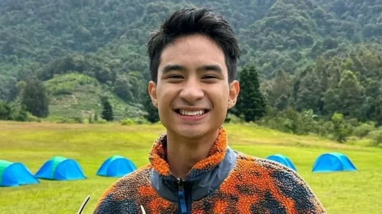 Potret Devano Danendra tersenyum di alam terbuka dengan latar belakang tenda.