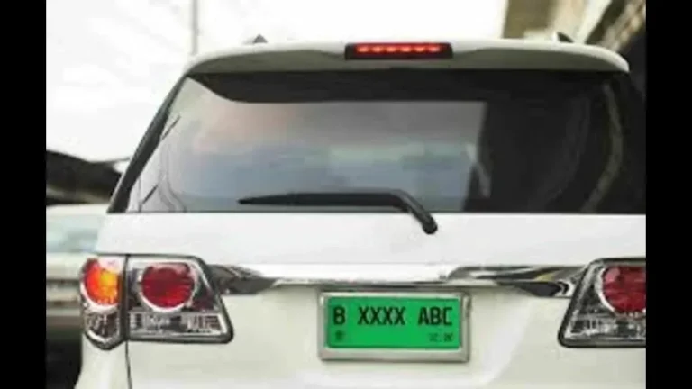 Bagian belakang mobil putih dengan pelat nomor hijau bertuliskan B XXXX ABC.