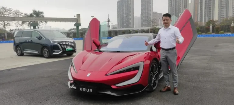 Mobil sport listrik merah BYD dengan pintu terbuka, seorang pria memberikan dua jempol.