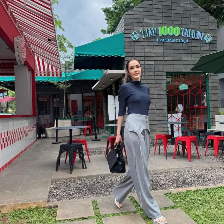 Cathy Sharon berjalan di depan restoran, tampil modis dan awet muda.