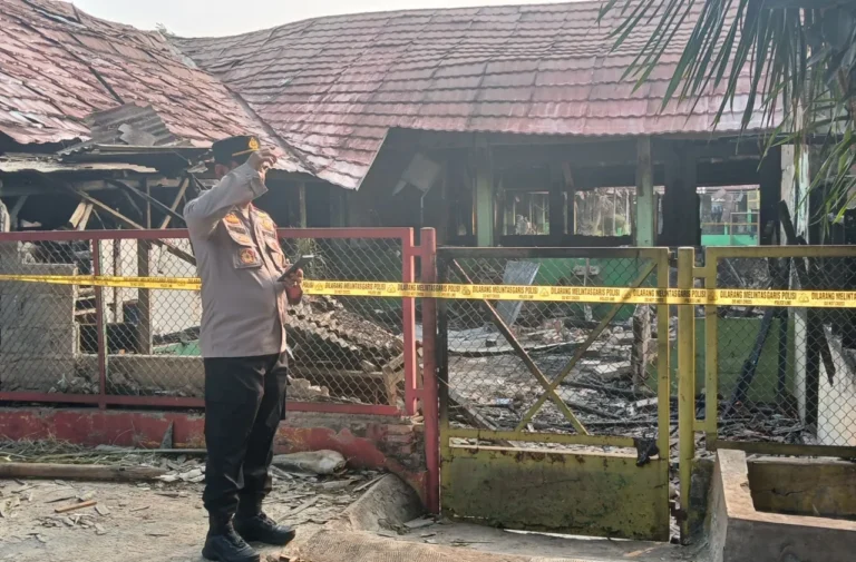 Polisi di lokasi kebakaran sekolah, garis polisi terpasang.