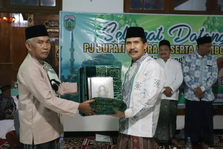 Dua pria berpeci bertukar bingkisan berupa sajadah dan Al-Quran.