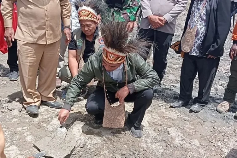 Pria berpakaian adat sedang bekerja dengan semen di tanah.