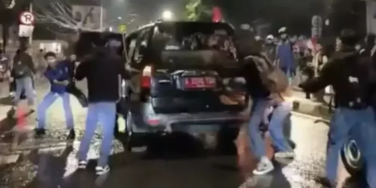 Massa merusak mobil dinas berplat merah di Slipi, Jakarta Barat, malam hari.