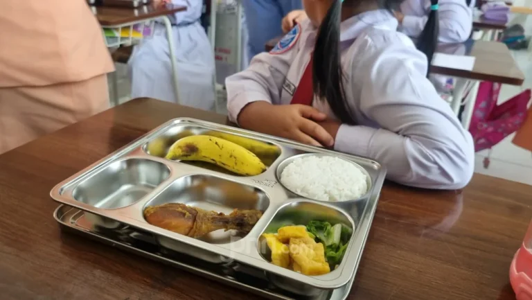 Menu makan siang bergizi gratis untuk siswa dengan nasi, ayam, pisang, dan sayur lengkap.