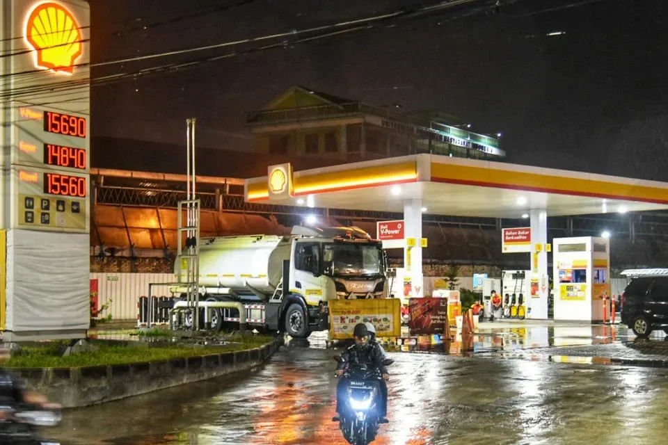 SPBU Shell malam hari dengan truk tangki dan motor di Jabodetabek.