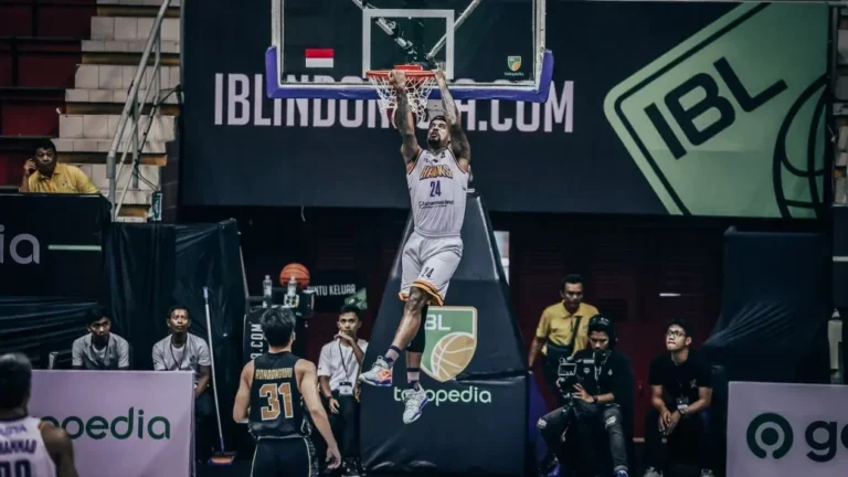Aksi pemain basket melompat memasukkan bola ke ring dalam laga IBL.