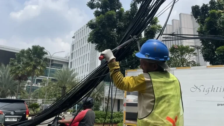 Pekerja sedang menata kabel semrawut di jalanan Tangerang Selatan.