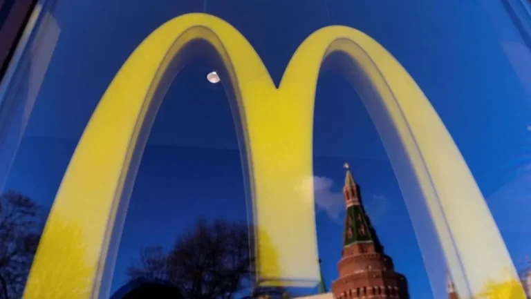 Logo McDonald's terpantul di jendela, dengan bayangan bangunan khas Rusia.