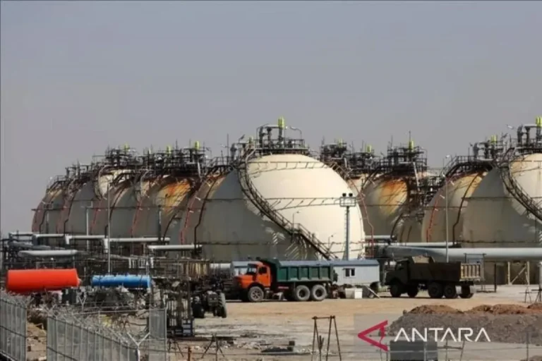 Tangki besar di lokasi industri, truk terlihat di foreground.
