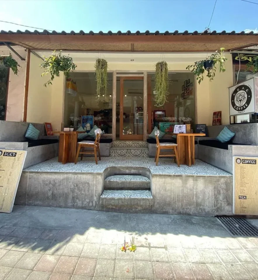 Fasad kafe estetik di Ubud, Bali dengan dekorasi tanaman gantung dan kursi kayu.