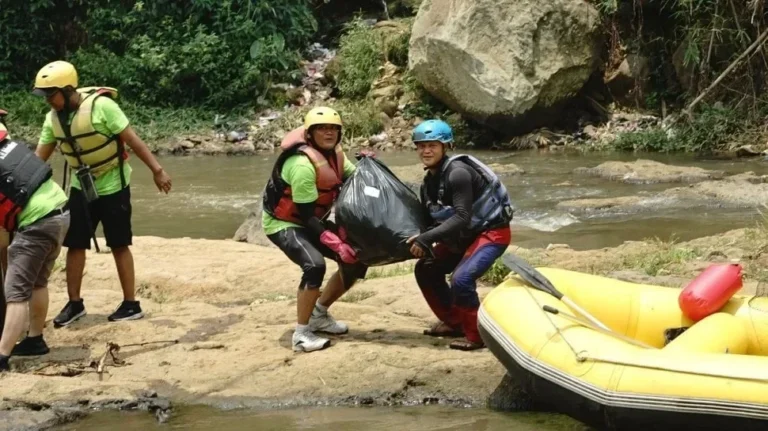 Relawan membersihkan sampah di Sungai Cisadane menggunakan perahu karet dan perlengkapan keselamatan.