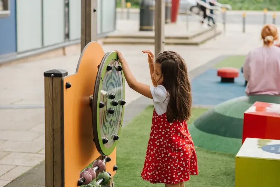 Wahana Park, Side view of little girl playing with toy on playground in casual outfit in daytime on street