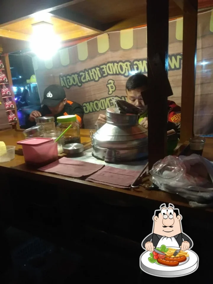 Dua pria menikmati wedang ronde di warung kaki lima pada malam hari.