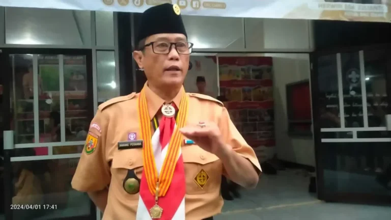 Pria berkacamata memakai peci dan seragam Pramuka, Nanang Permana, sedang berbicara.