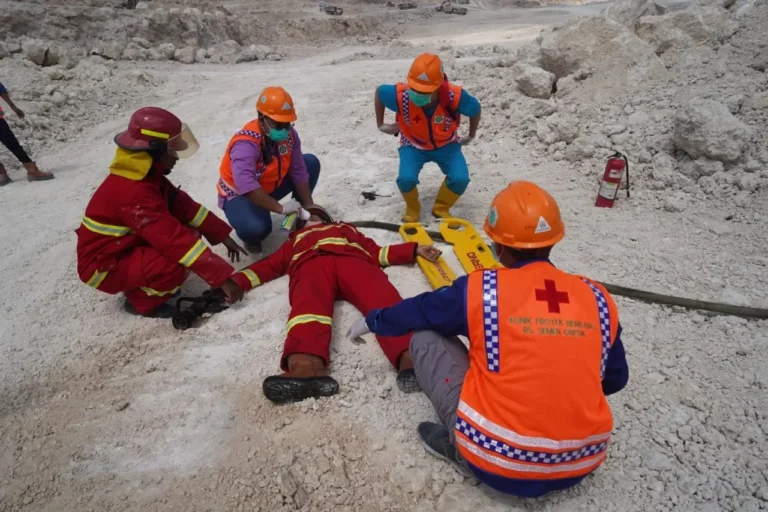 Simulasi penanganan korban kecelakaan kerja oleh tim medis dan penyelamat di area proyek pertambangan.