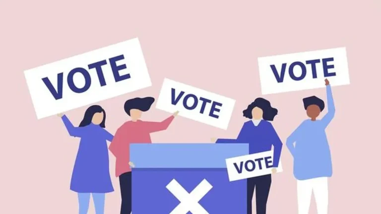 Ilustrasi sekelompok orang memegang papan "VOTE" di sekitar kotak suara.