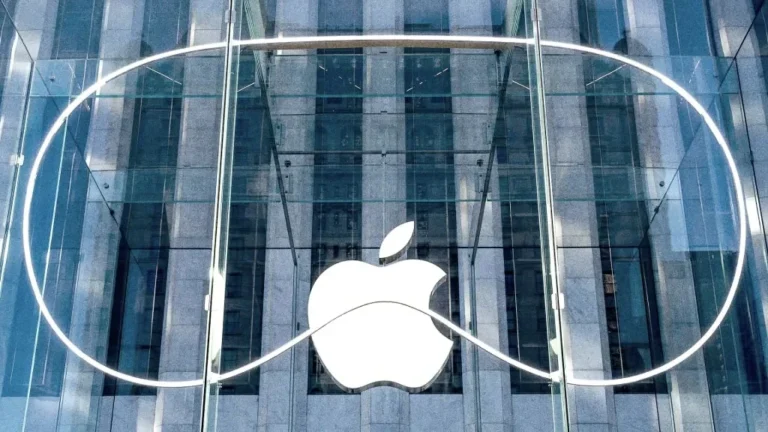 Logo Apple yang ikonik terpampang di fasad kaca sebuah bangunan modern.