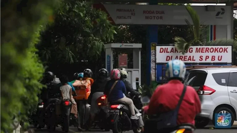 Antrean kendaraan roda dua di SPBU Pertamina dengan rambu peringatan keselamatan.