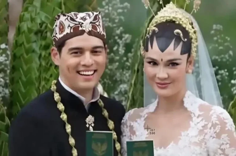 Pasangan pria dan wanita tersenyum mengenakan pakaian adat pernikahan tradisional Indonesia.