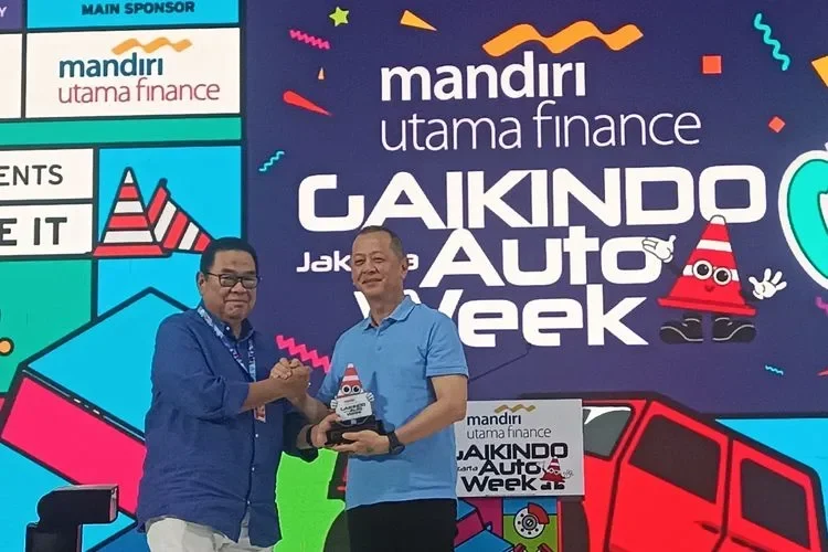 Dua pria berjabat tangan di panggung acara Gaikindo Auto Week dengan logo Mandiri Utama Finance.