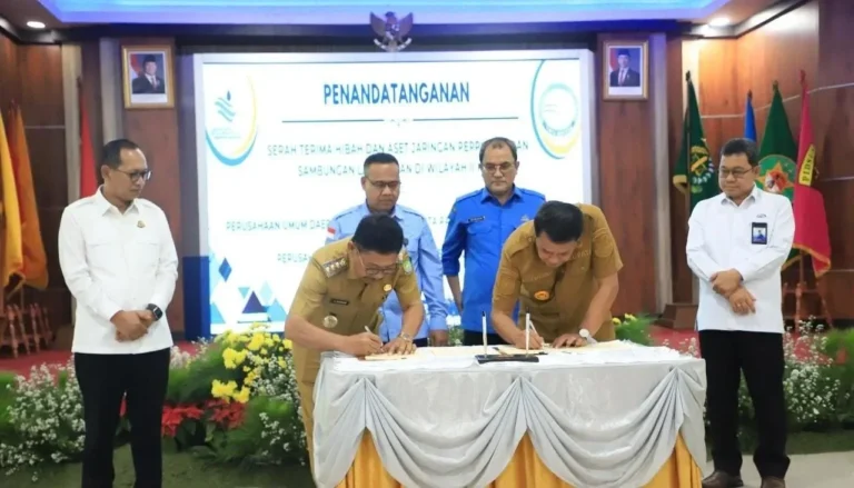 Dua pejabat menandatangani dokumen serah terima aset pelayanan air bersih.