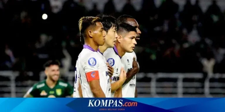 Empat pemain sepak bola berjersey putih dari sebuah tim terlihat fokus di lapangan saat pertandingan.