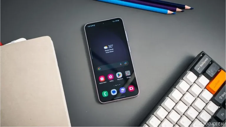 Smartphone Samsung menampilkan ikon aplikasi dan widget cuaca di meja kerja bersama keyboard.