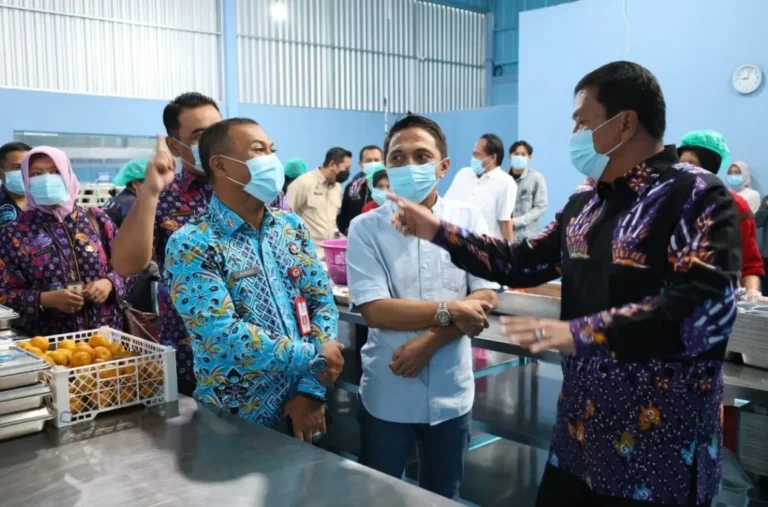 Pejabat mengenakan masker meninjau fasilitas produksi makanan, memeriksa proses dan produk olahan.