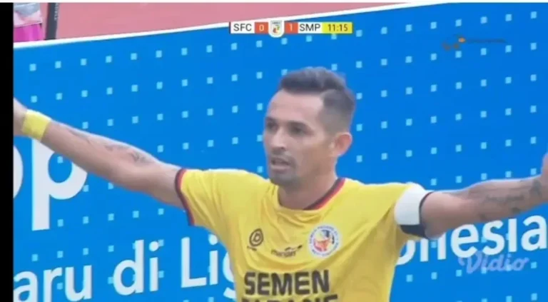 Pemain Semen Padang berjersey kuning merayakan di lapangan sepak bola saat pertandingan.