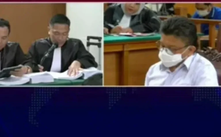 Terdakwa bermasker mendengarkan persidangan dengan tim kuasa hukum di pengadilan.