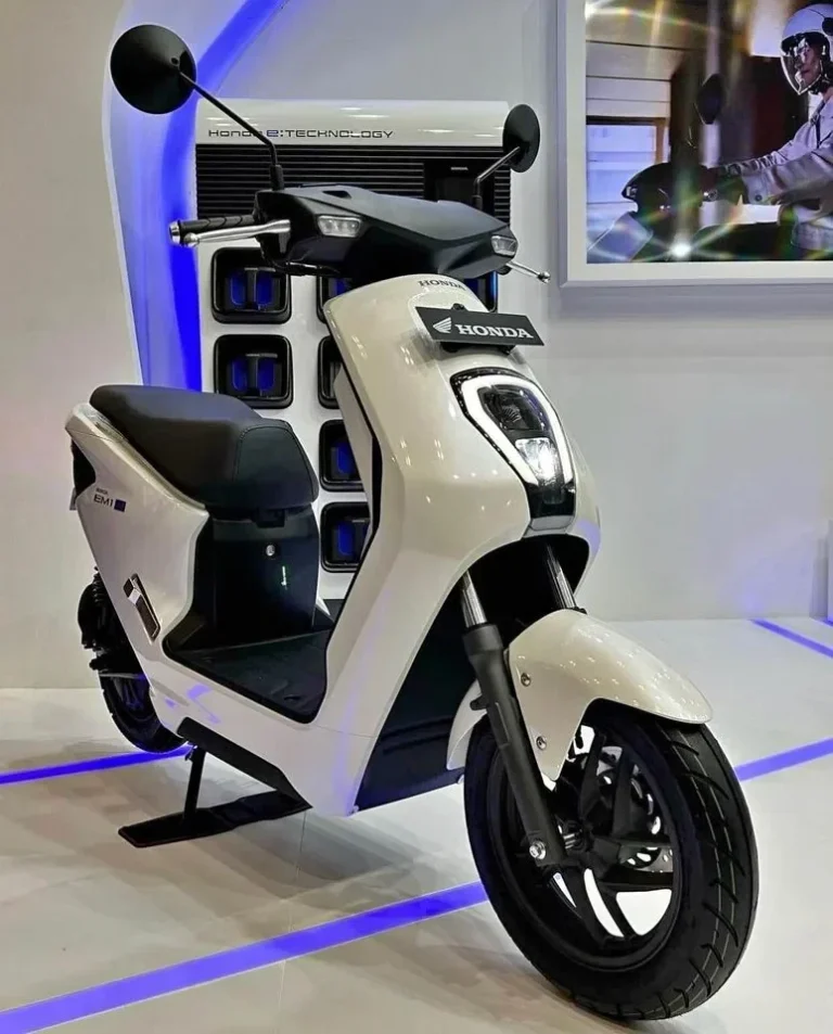Skuter listrik Honda EM1 e: berwarna putih dipamerkan bersama stasiun penukaran baterai.