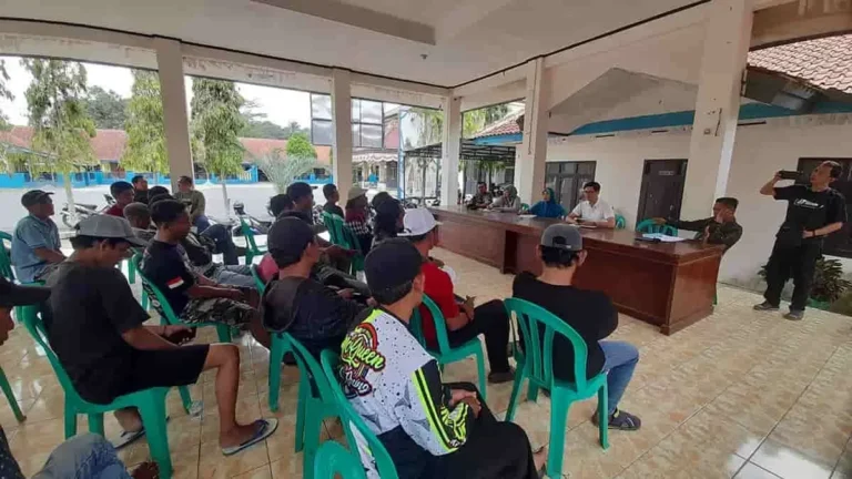 Peserta mendengarkan penjelasan dalam pertemuan warga yang dihadiri beberapa pejabat di balai desa.