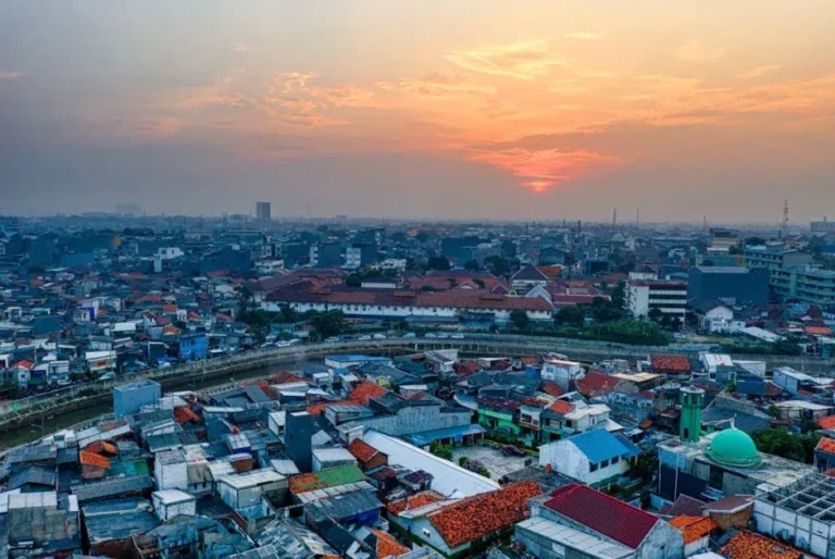 A stunning aerial view of an urban cityscape at sunset with vibrant skies and dense housing.