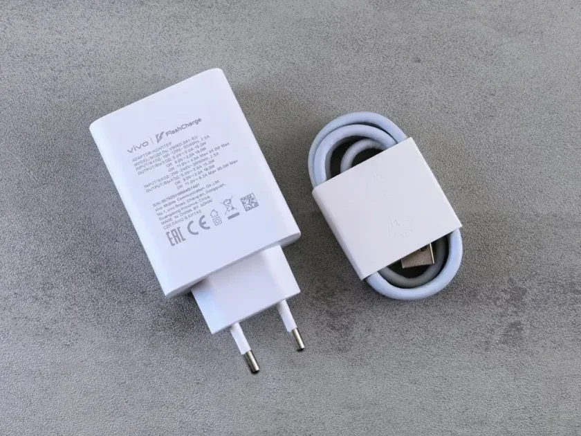 Close-up of Vivo FlashCharge adapter with cable on a textured concrete background, highlighting modern charging technology.